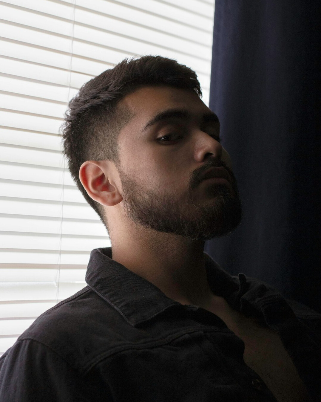 Portrait of a man with short hair and a beard in a casual shirt